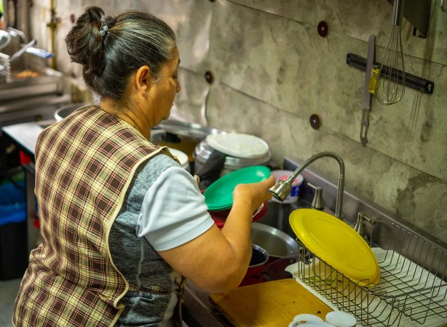 Black and white portrait of a housekeeper with cleaning supplies in a modern kitchen.